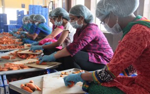 Volunteers are seen helping Akshaya Patra kitchen staff in prepping for the next day’s meals