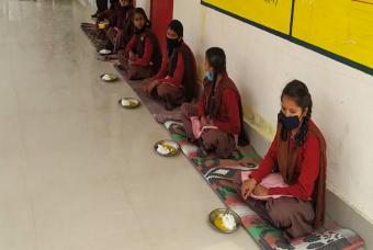 Children receive their mid-day meals after their schools reopen